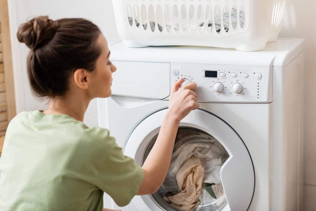 kobieta ustawia tryb eco na pralce - oszczędzanie energii